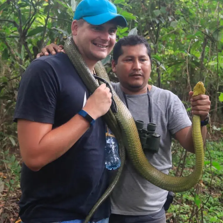Guests holding a large snake with the guide